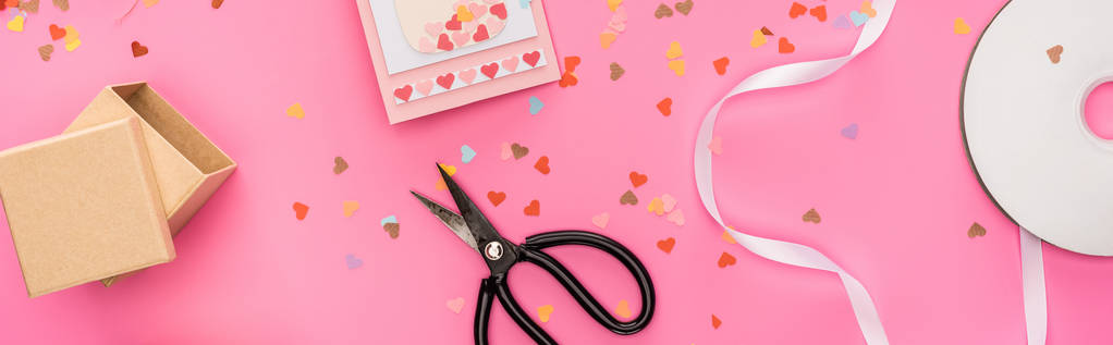 bovenaanzicht van valentijnskaart confetti, lege compact disk, geschenkdoos, wenskaart, schaar op roze achtergrond, panoramisch shot - Foto, afbeelding