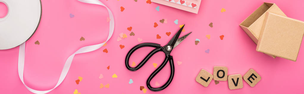 bovenaanzicht van valentijnskaarten confetti, lege compact disk, schaar, geschenkdoos, wenskaart en liefdesbelettering op houten blokjes op roze achtergrond, panoramisch shot - Foto, afbeelding