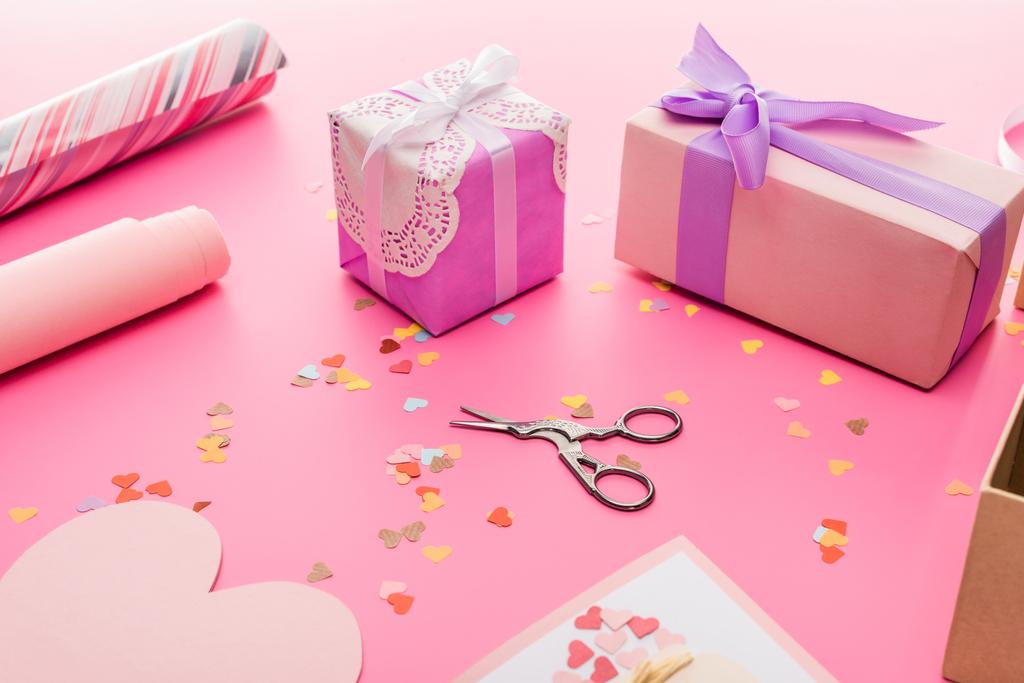 валентинки конфетті, ножиці, обгортковий папір, подарункові коробки на рожевому фоні
 - Фото, зображення