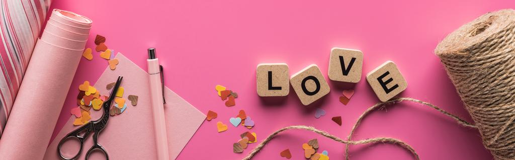 vista superior de la decoración de San Valentín, tijeras, papel de envolver, hilo y letras de amor en cubos de madera sobre fondo rosa, plano panorámico
 - Foto, imagen