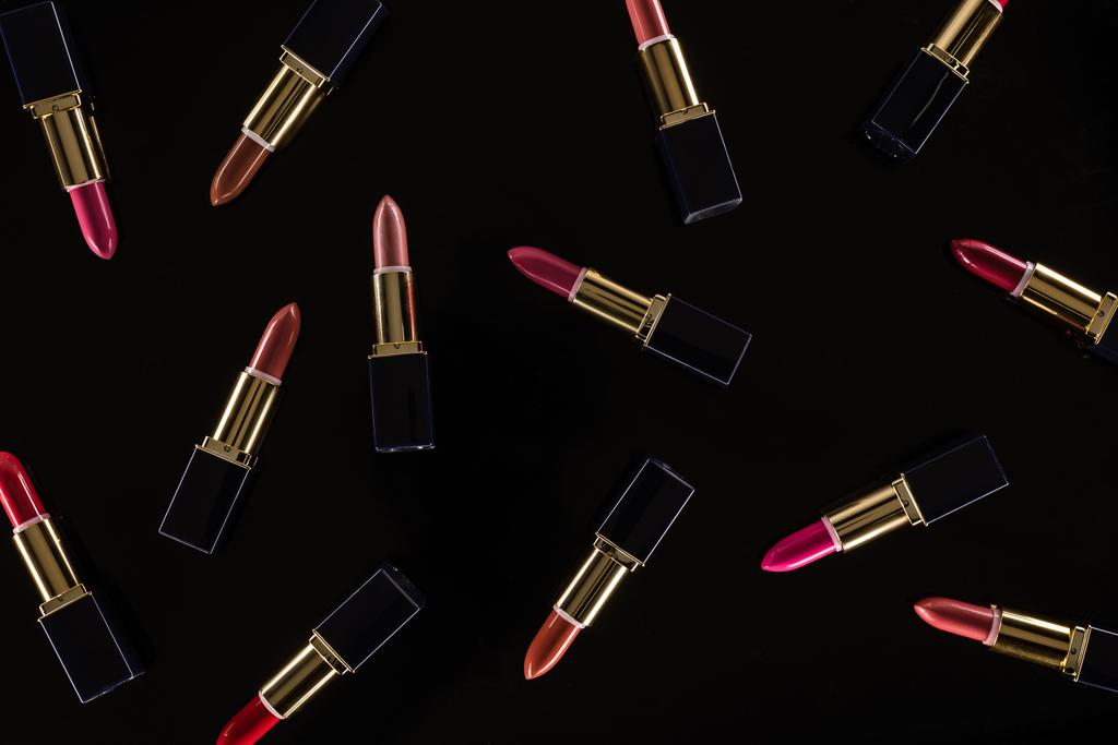 Draufsicht auf verschiedene Lippenstifte in Luxusröhrchen isoliert auf schwarz - Foto, Bild