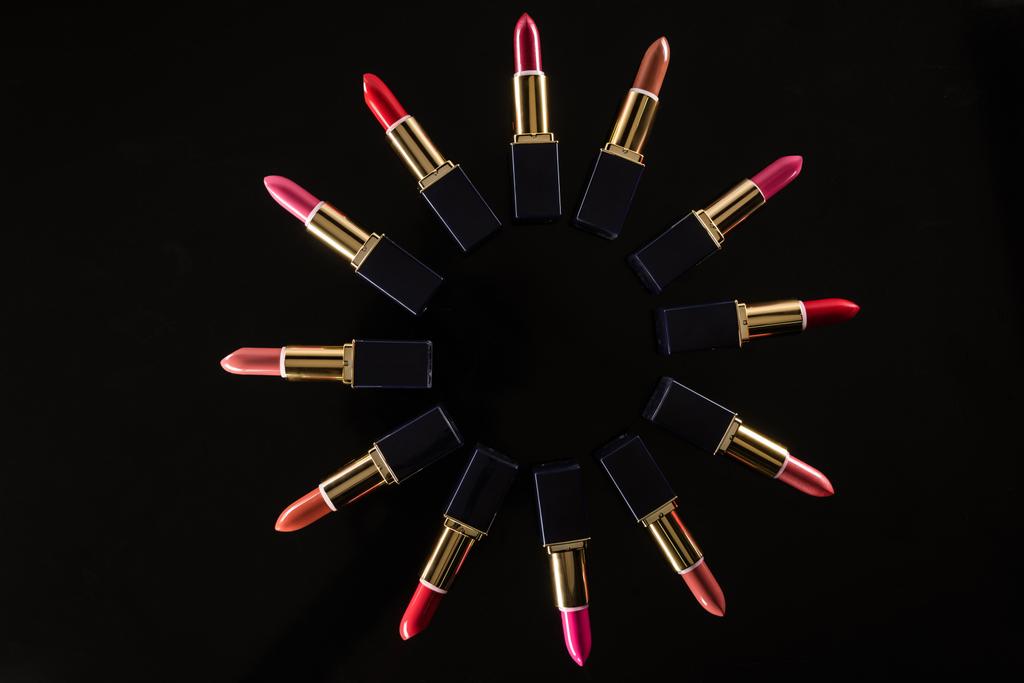 bovenaanzicht van diverse lippenstiften in luxe buizen in cirkel geïsoleerd op zwart - Foto, afbeelding