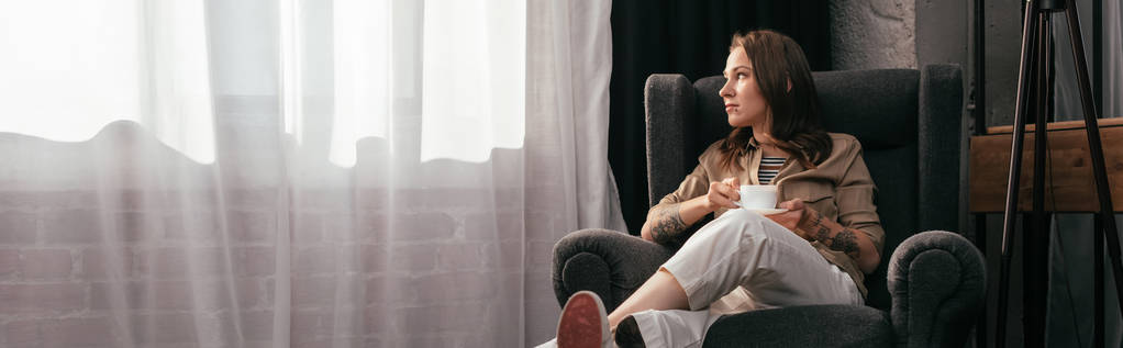 Foto panorámica de mujer joven con la pierna protésica bebiendo café en la sala de estar
 - Foto, Imagen