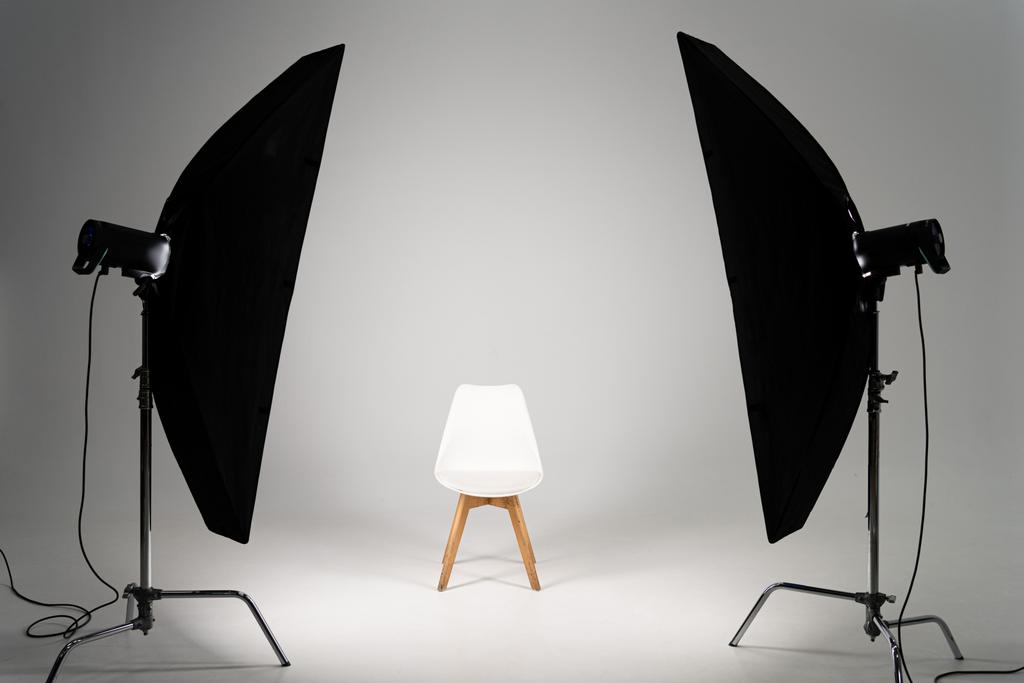 Wit moderne stoel met studiolampje op grijze achtergrond - Foto, afbeelding