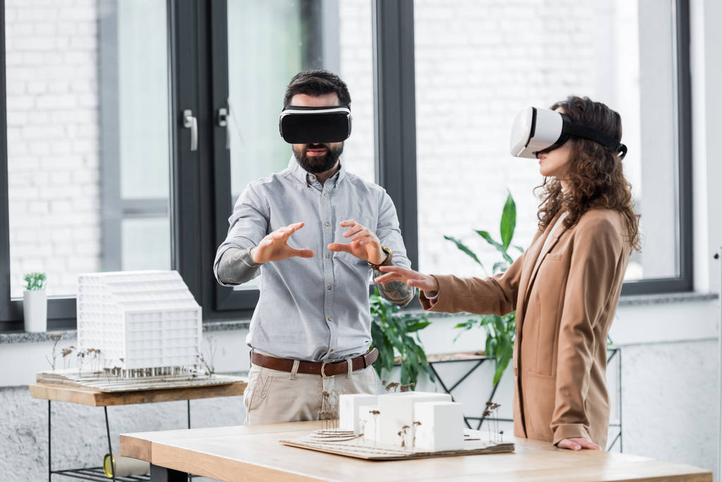virtual reality architects in virtual reality headsets gesturing and looking at model of house  - Photo, Image