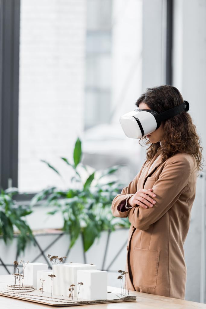 Seitenansicht des Virtual-Reality-Architekten im Virtual-Reality-Headset mit Blick auf das Hausmodell  - Foto, Bild