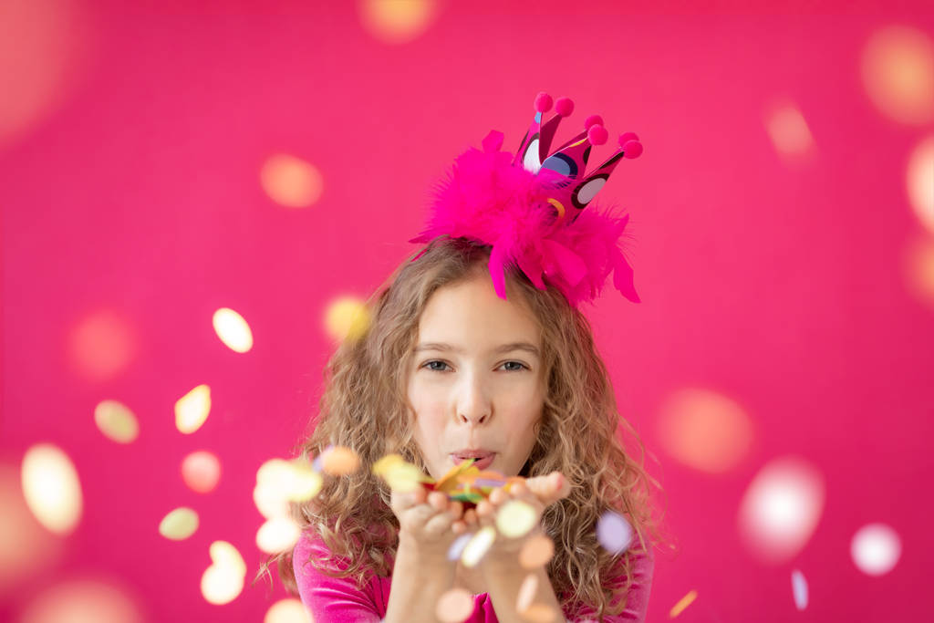 Fantasievolles Mädchen pustet Konfetti gegen rosa Backboden - Foto, Bild