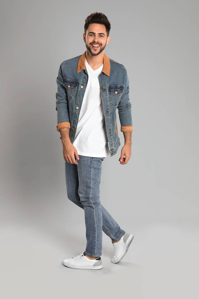 Mladý muž v stylové džíny na šedém pozadí - Fotografie, Obrázek
