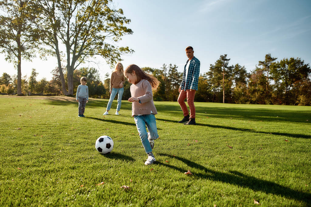 Віра, сім'я, футбол. Щаслива сім'я грає з м'ячем на лузі
 - Фото, зображення