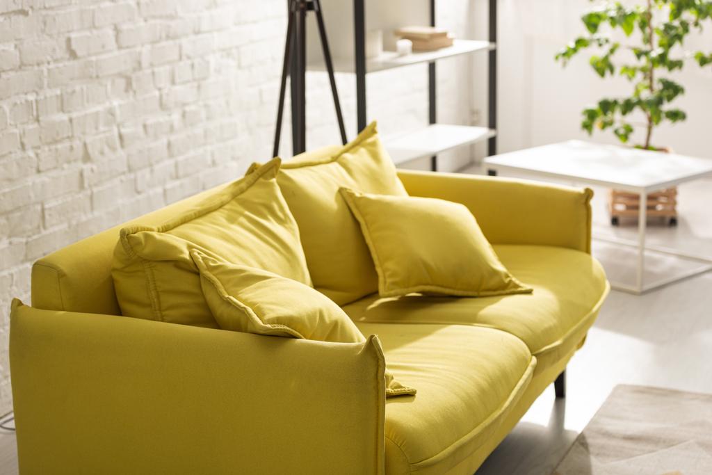 Άνετο κίτρινο καναπέ με ηλιακό φως στο σαλόνι - Φωτογραφία, εικόνα