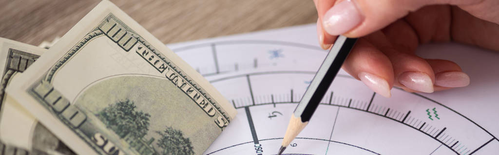 Обрезанный вид астролога рисующего натальную диаграмму с долларовыми банкнотами на столе, панорамный снимок
 - Фото, изображение