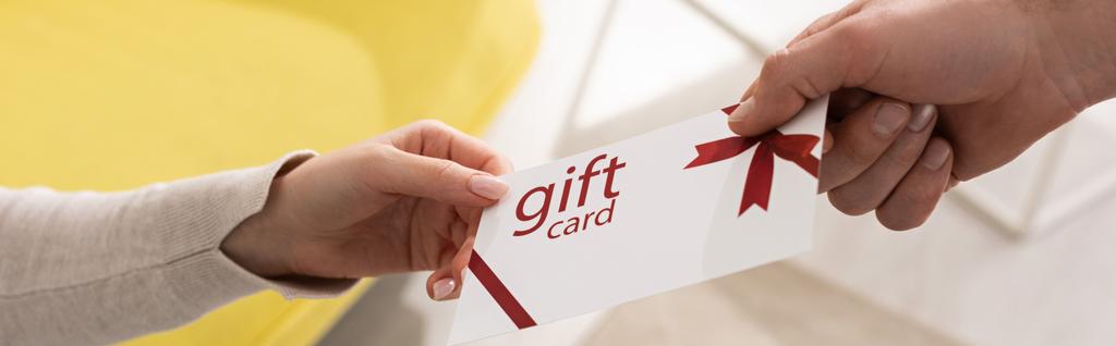 Cropped view of man giving gift card to woman, panoramic shot - 写真・画像