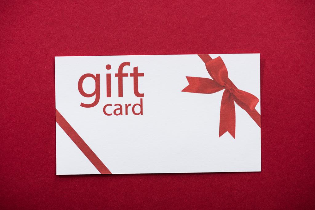 Kırmızı arkaplanda hediye kartının üst görünümü - Fotoğraf, Görsel