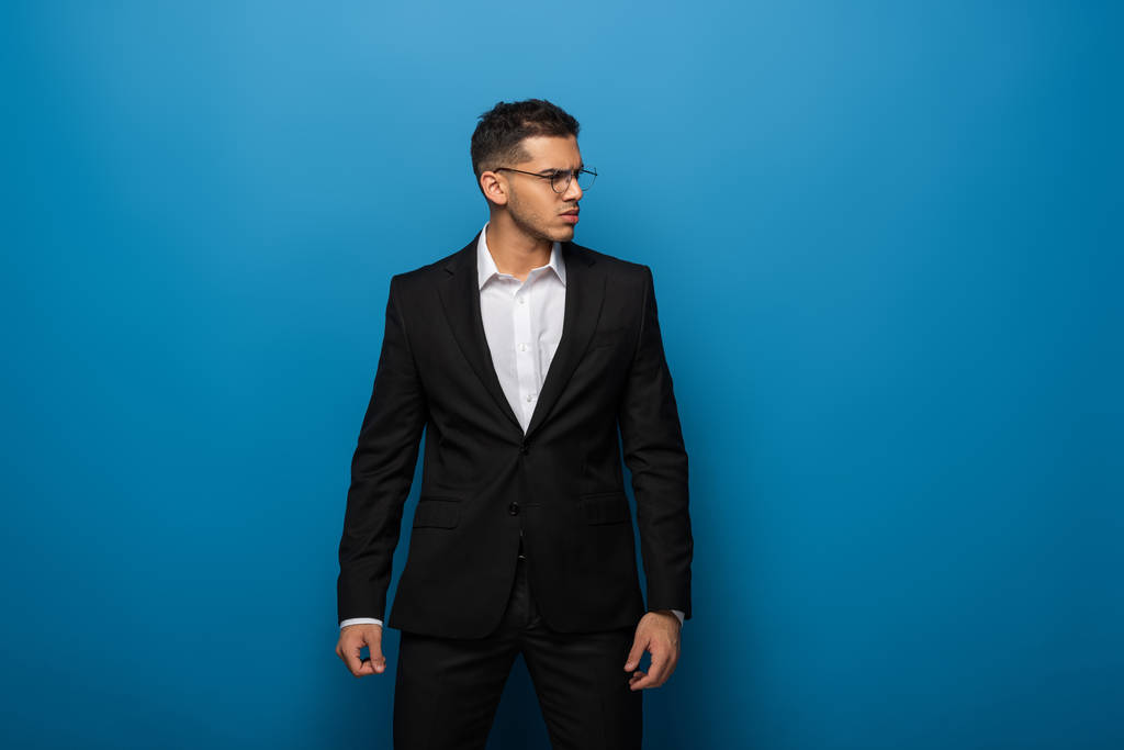 Handsome businessman looking away on blue background - Photo, Image