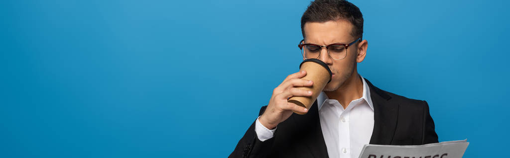Panoramisch schot van zakenman drinken van koffie en het lezen van krant geïsoleerd op blauw - Foto, afbeelding