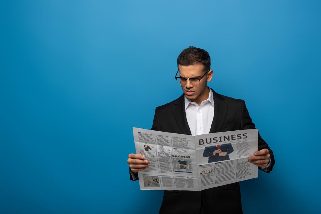 Przemyślany biznesmen czytający gazety na niebieskim tle - Zdjęcie, obraz