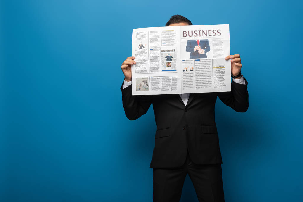 Uomo d'affari che copre il viso con giornale su sfondo blu
 - Foto, immagini
