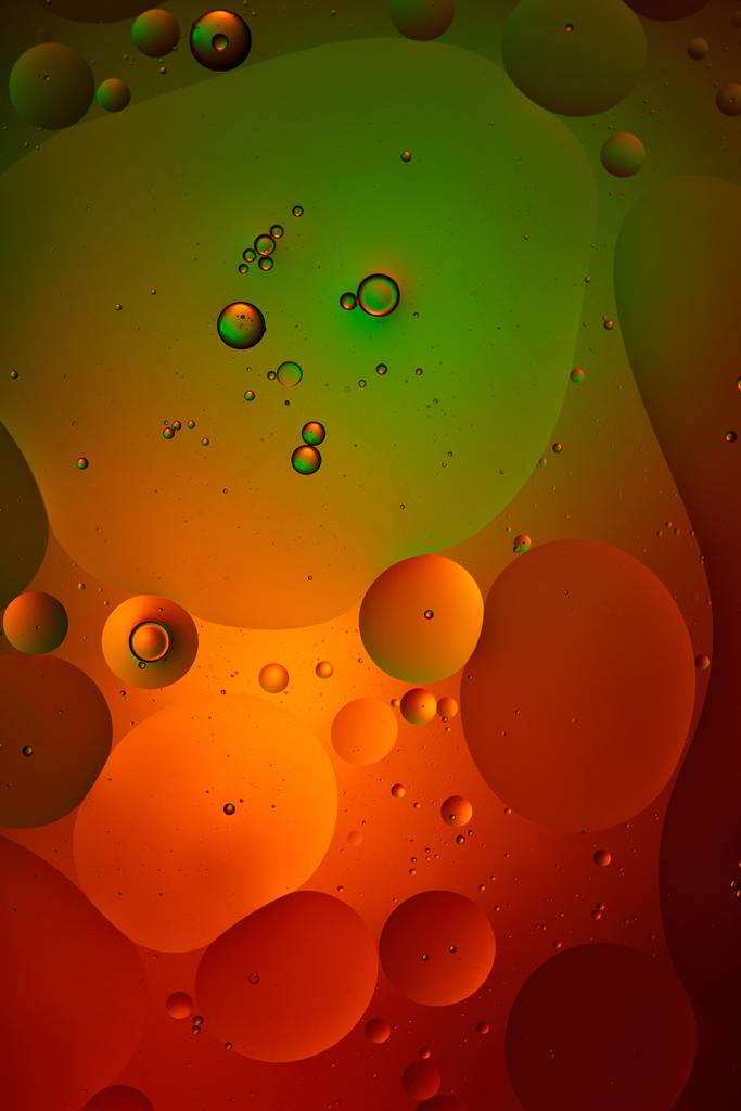 緑色と赤色の混合水と油泡からの抽象的な背景 - 写真・画像