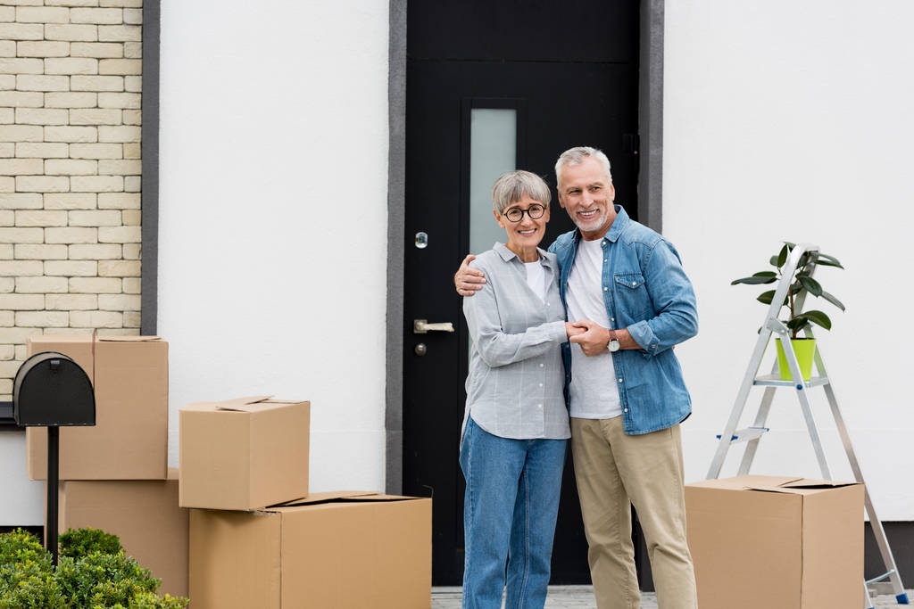 souriant mature homme et femme étreignant près de nouvelle maison
  - Photo, image