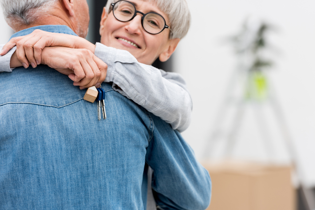 cropped view of smiling woman holding keys of new house and hugging mature man  - Photo, Image