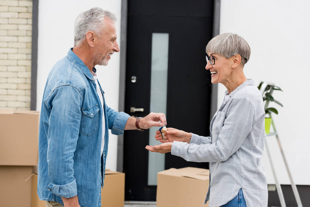 side view of mature man giving keys of new house to smiling woman  - Photo, Image