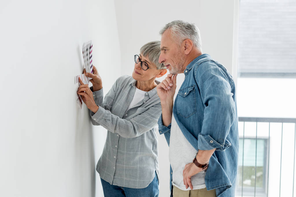 mietteliäs mies ja kypsä nainen katselee paletti uudessa talossa
  - Valokuva, kuva