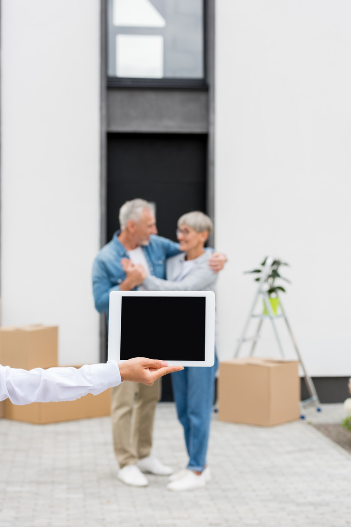 селективный фокус брокера, держащего цифровой планшет, и пары, стоящей рядом с новым домом на заднем плане
  - Фото, изображение