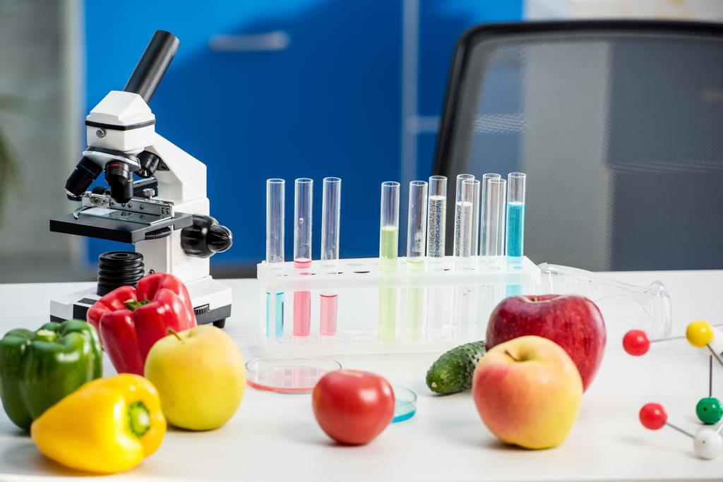 μικροσκόπιο, φρούτα, λαχανικά, δοκιμαστικοί σωλήνες στο τραπέζι στο εργαστήριο  - Φωτογραφία, εικόνα