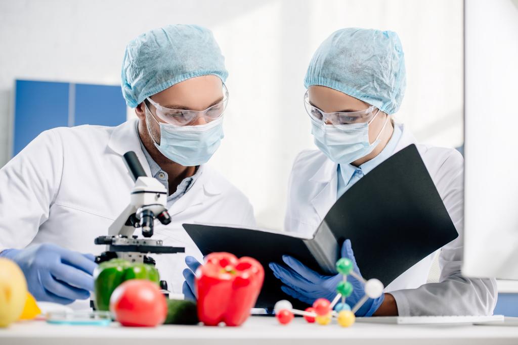 selective focus of molecular nutritionists looking at folder in lab  - Photo, Image