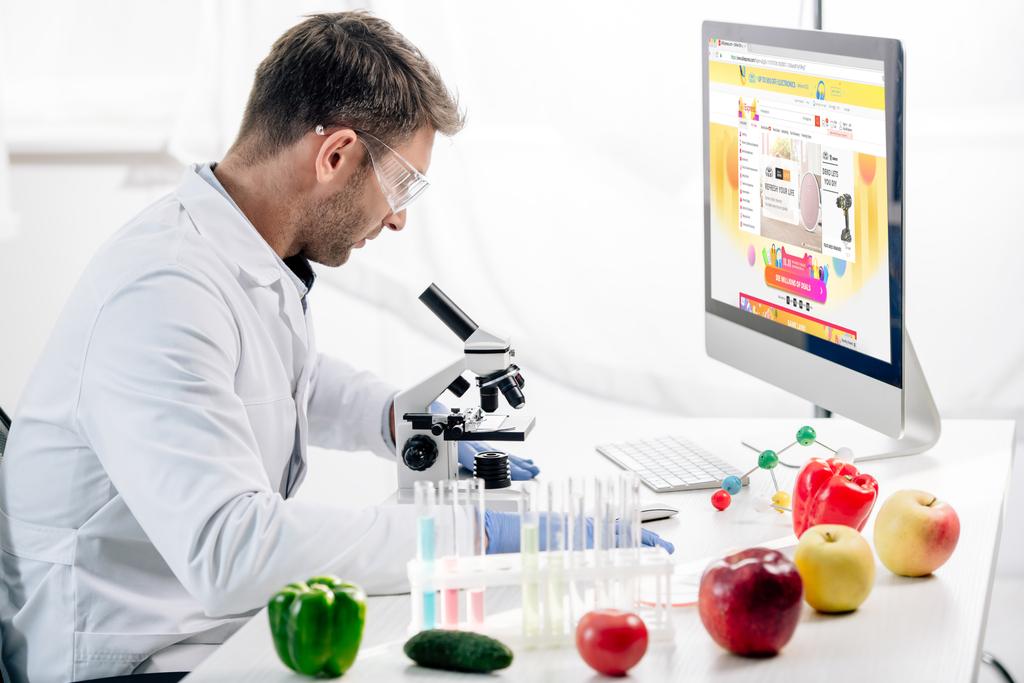 KYIV, UKRAINE - OCTOBER 4, 2019: side view of molecular nutritionist using computer with aliexpress website  - Photo, Image