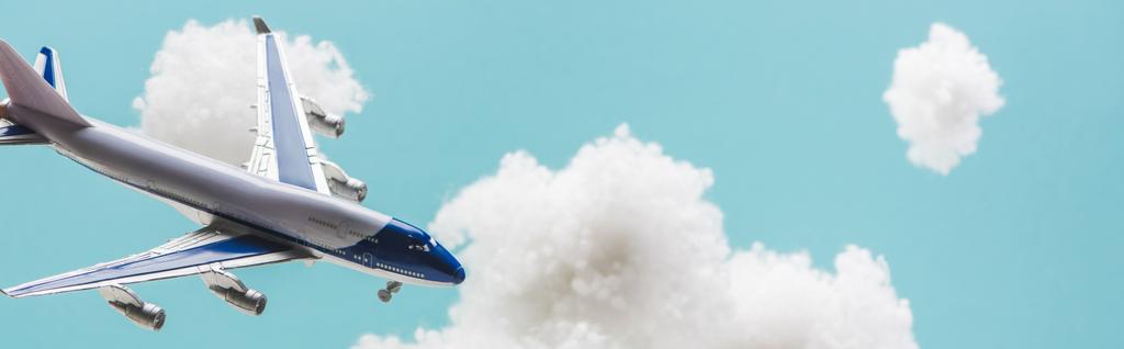 παιχνίδι αεροπλάνο που φέρουν μεταξύ λευκό αφράτο σύννεφα από μαλλί βαμβάκι που απομονώνονται σε μπλε, πανοραμική βολή - Φωτογραφία, εικόνα