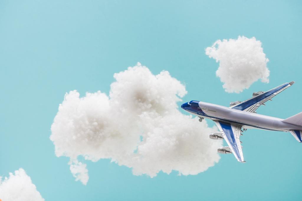 Beyaz pamuklu bulutların arasında uçan oyuncak uçak mavi üzerinde izole edilmiş pamuk yününden - Fotoğraf, Görsel