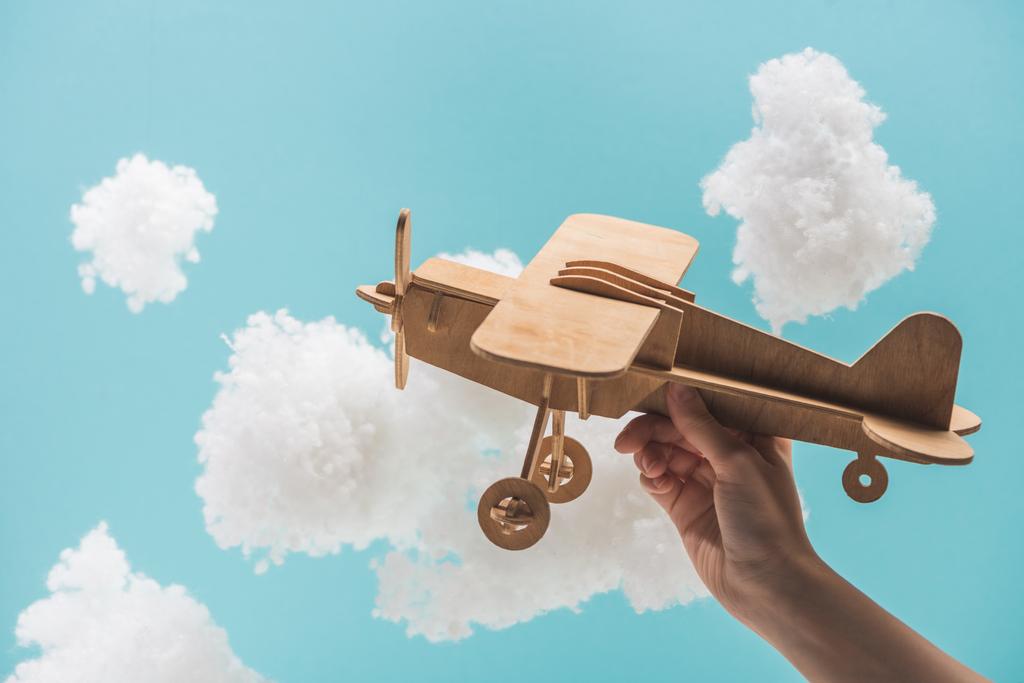 avion jouet en bois volant parmi les nuages duveteux blancs en laine de coton isolé sur bleu
 - Photo, image