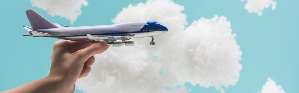 обрізаний вид жінки, що грає з іграшковою площиною серед білих пухнастих хмар з вати ізольовані на синьому, панорамний постріл
 - Фото, зображення