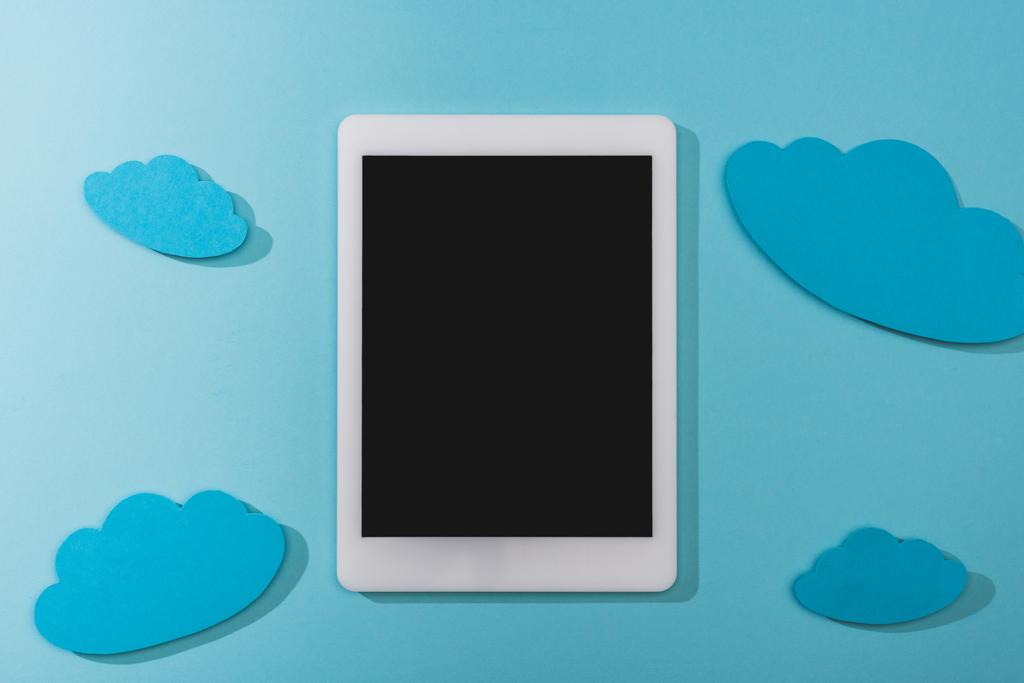 ylhäältä tyhjät paperipilvet lähellä digitaalista tablettia tyhjällä näytöllä sinisellä
 - Valokuva, kuva