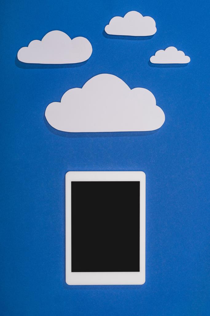 Beyaz kağıdın üst görünümü mavi arkaplanda bulutları ve dijital tableti keser - Fotoğraf, Görsel