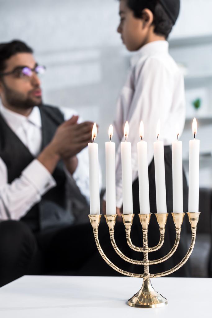 selective focus of candlestick with candles and jewish father and son on background  - Photo, Image