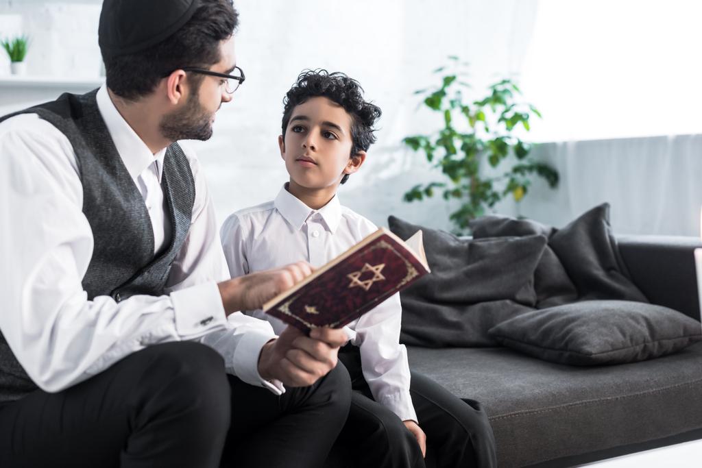 zsidó apa és fia beszél és tartja tanakh a lakásban  - Fotó, kép