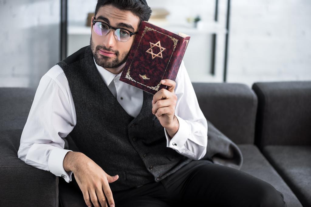 knappe joodse man met bril tanakh en kijken naar de camera  - Foto, afbeelding