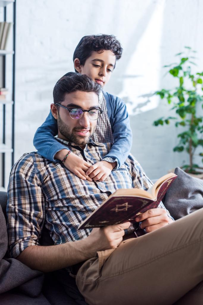 usmívající se židovský otec a syn čtení tanakh v bytě  - Fotografie, Obrázek