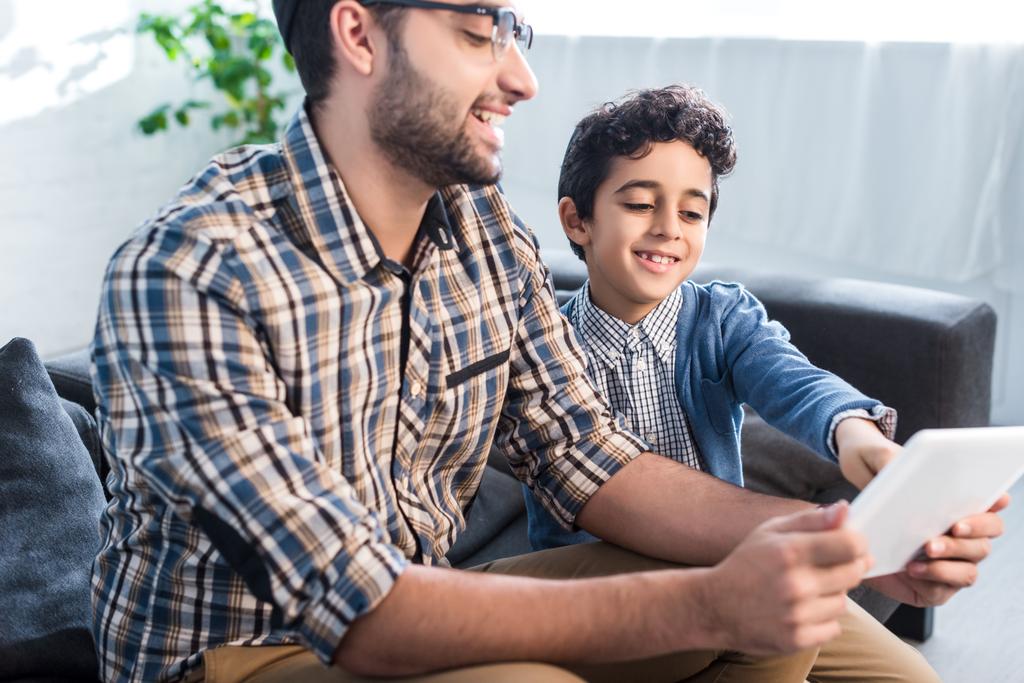 padre e figlio ebreo sorridente utilizzando tablet digitale in appartamento
  - Foto, immagini
