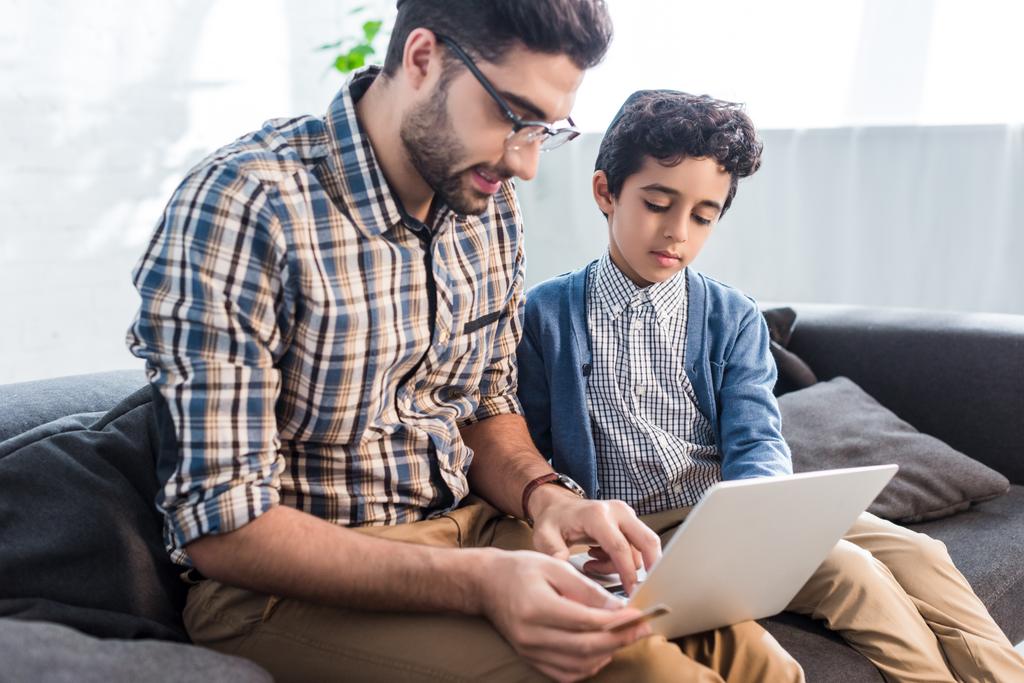 еврейский отец и милый сын с помощью ноутбука в квартире
  - Фото, изображение