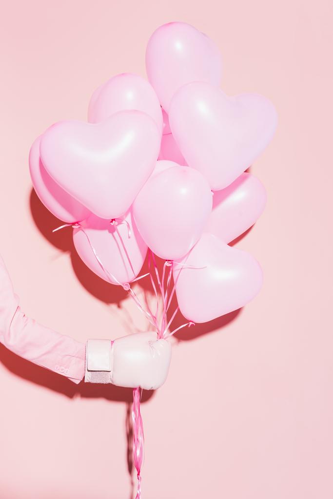 cropped view of woman in boxing glove holding balloons on pink background  - Photo, Image