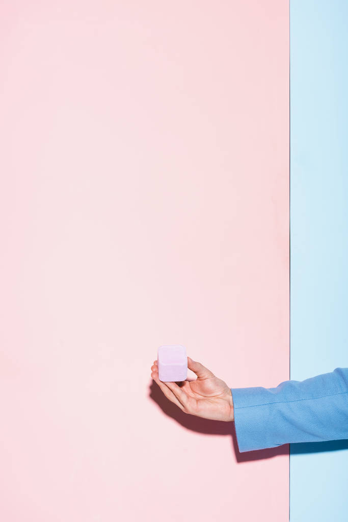 καλλιεργημένη άποψη του άνδρα κρατώντας κουτί σε μπλε και ροζ φόντο  - Φωτογραφία, εικόνα