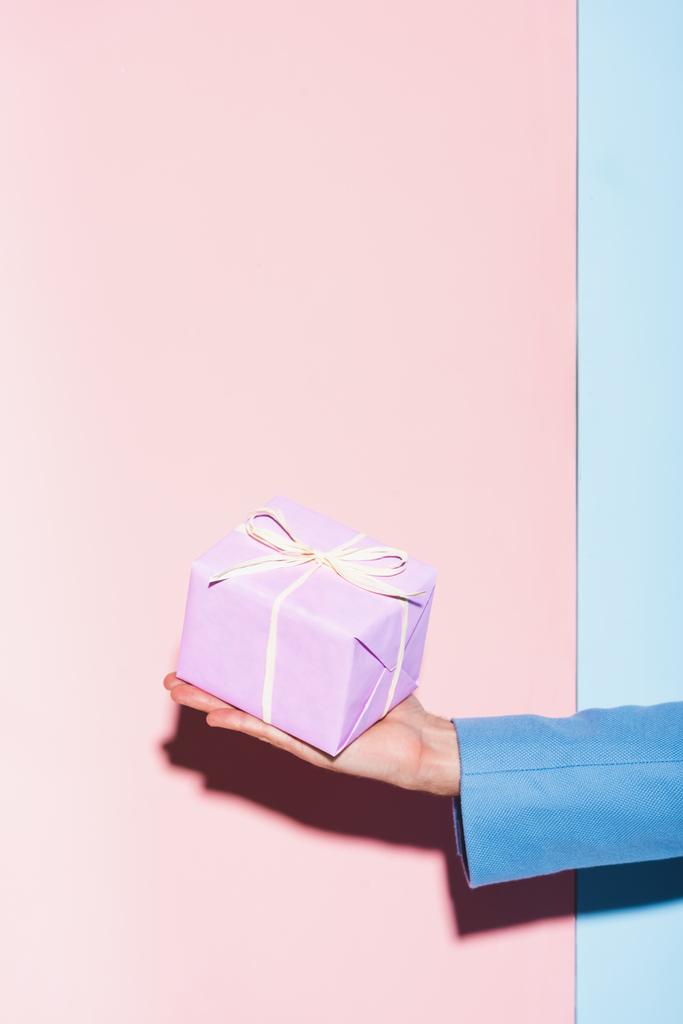 cropped view of man holding gift on blue and pink background  - Photo, Image
