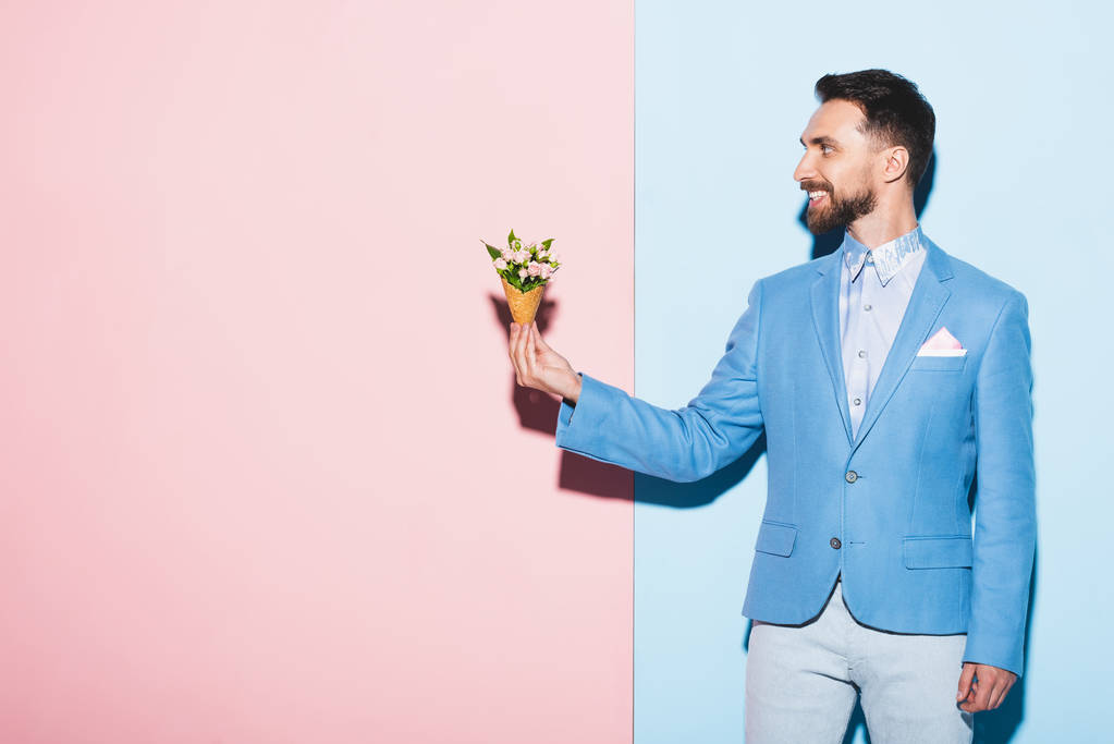 mosolygós férfi gazdaság csokor rózsaszín és kék háttér  - Fotó, kép