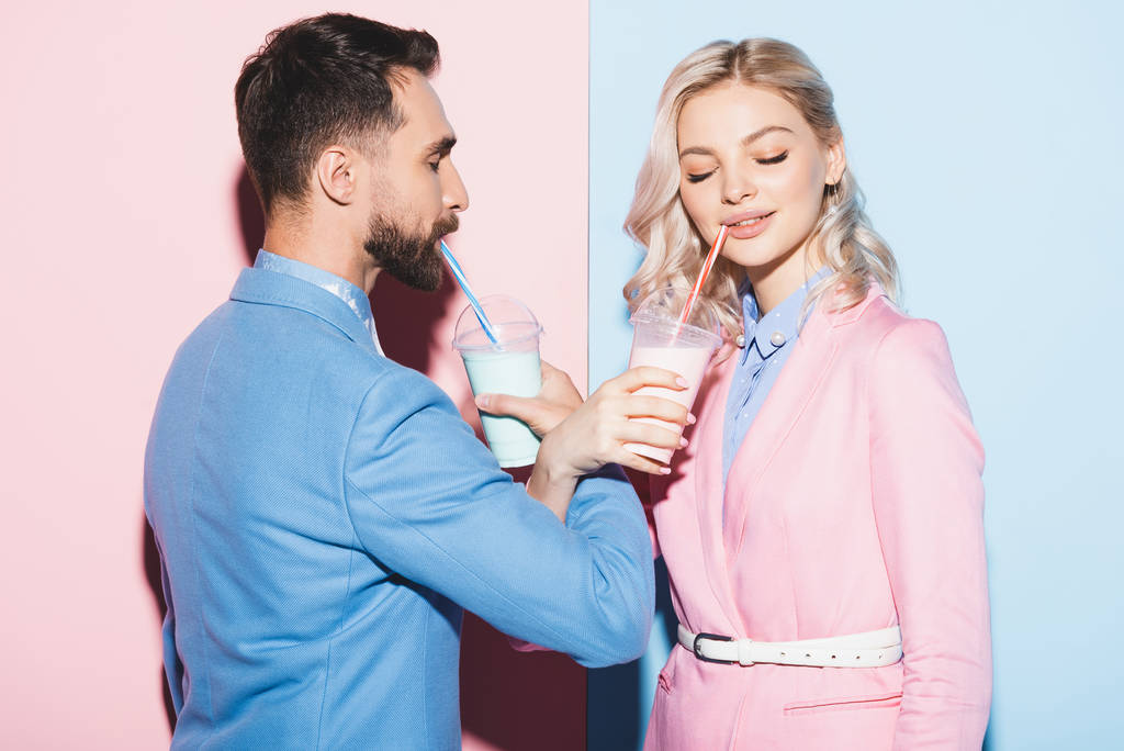donna sorridente e uomo bere cocktail su sfondo rosa e blu
  - Foto, immagini
