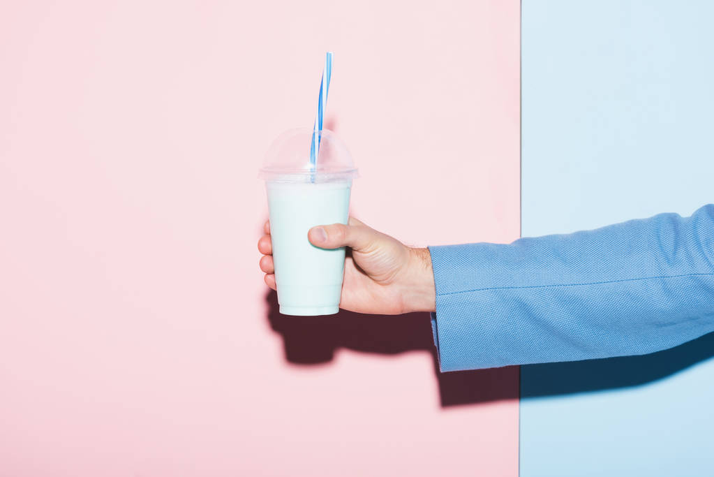 cropped view of man holding cocktail on pink and blue background  - Photo, Image