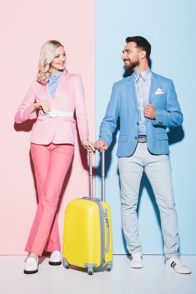 femme souriante et bel homme avec sac de voyage sur fond rose et bleu
  - Photo, image