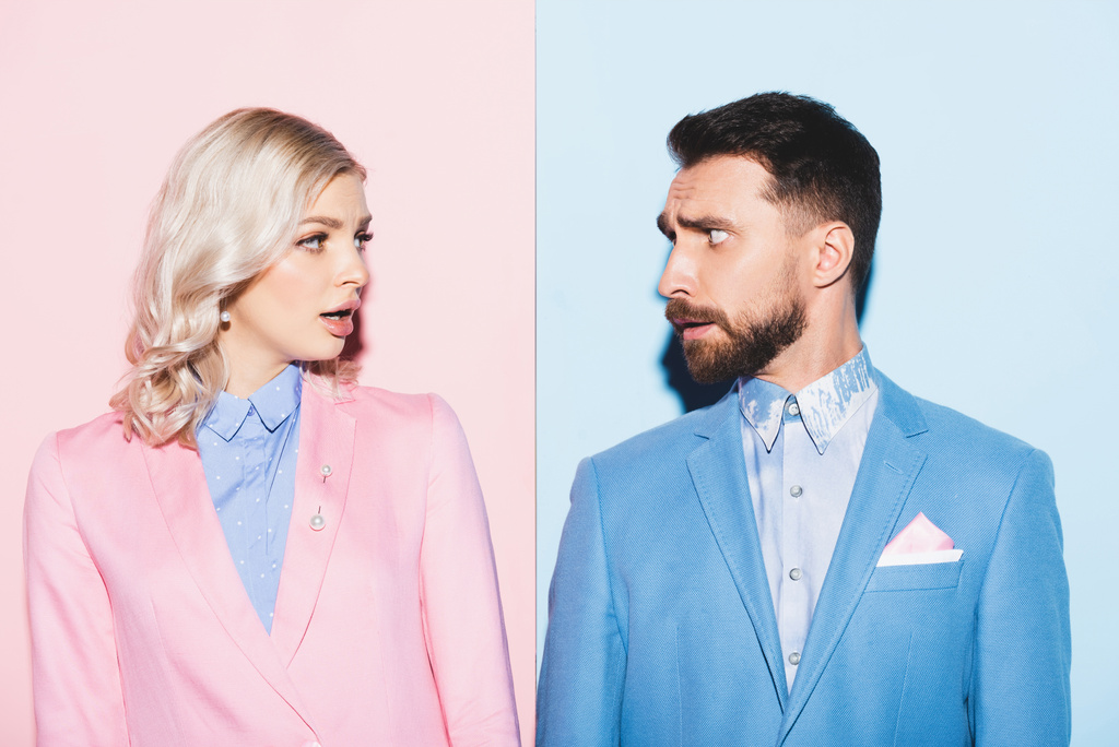 geschokte vrouw en knappe man kijken naar elkaar op roze en blauwe achtergrond  - Foto, afbeelding
